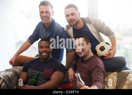 Gruppo di amici maschi con bandiera italiana di vernice faccia tenendo il calcio e bottiglie di birra guardando sorridente della fotocamera Foto Stock