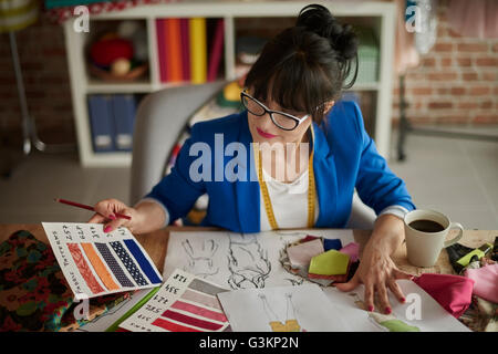 La donna nel design studio seduto alla scrivania guardando i campioni di colore Foto Stock