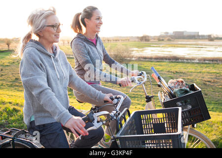 Vista laterale di donne in bicicletta dalla palude sorridente Foto Stock