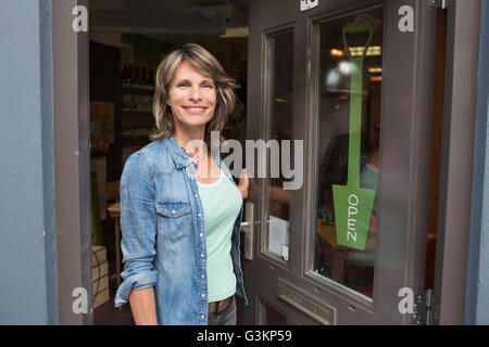 Donna in piedi nella porta del negozio Foto Stock