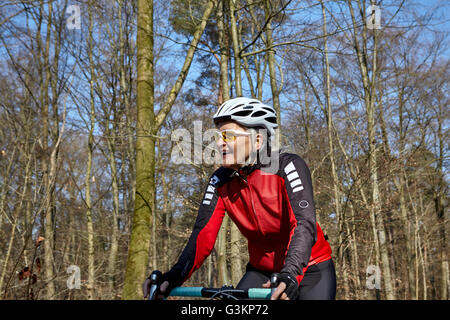 Donna che indossa il ciclismo casco e occhiali da sole ciclismo, guardando lontano sorridente Foto Stock