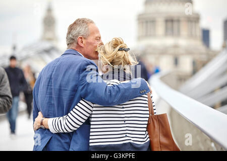 Vista posteriore della romantica mature dating giovane crossing Millennium Bridge, London, Regno Unito Foto Stock