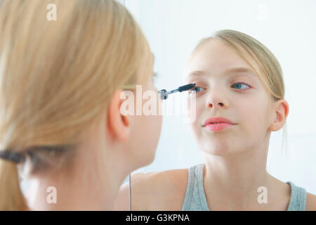 Oltre la spalla immagine speculare della ragazza applicazione di mascara Foto Stock