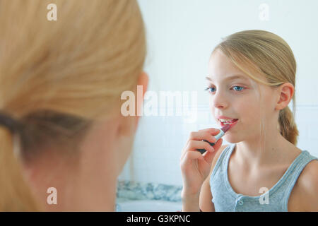 Oltre la spalla immagine speculare della ragazza il rossetto Foto Stock