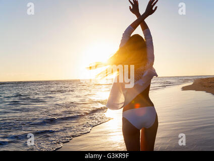 Vista posteriore del giovane donna ballando con le braccia sollevate sulla spiaggia, Repubblica Dominicana, Caraibi Foto Stock