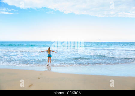 Vista posteriore della giovane donna in esecuzione in mare, Repubblica Dominicana, Caraibi Foto Stock