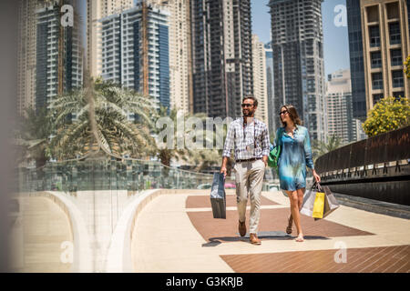 Turista giovane passeggiando sul marciapiede il trasporto delle borse della spesa, Dubai, Emirati Arabi Uniti Foto Stock