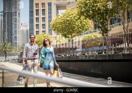 Giovane passeggiando sul marciapiede il trasporto delle borse della spesa, Dubai, Emirati Arabi Uniti Foto Stock