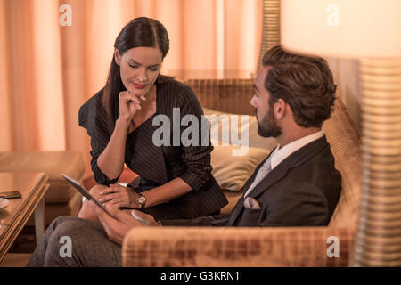 Imprenditore e donna seduta sul divano hotel usando tavoletta digitale Foto Stock