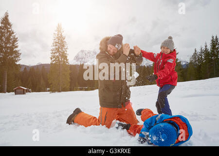 Uomo e figli aventi lotta con le palle di neve in inverno, Elmau, Baviera, Germania Foto Stock