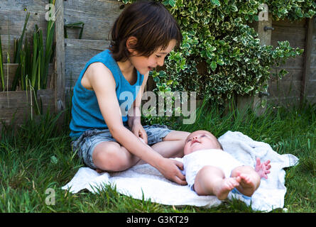 Ragazzo solletico baby fratello in giardino Foto Stock