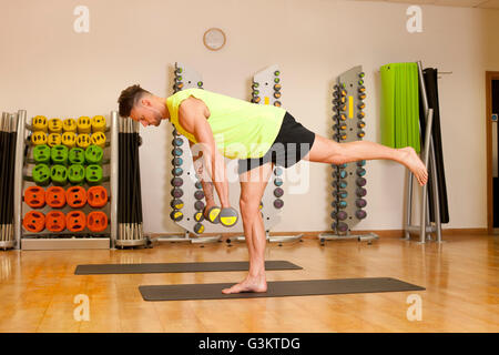 Uomo in palestra che esercitano sul materassino yoga con manubri Foto Stock