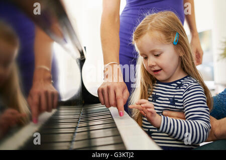 I genitori insegnare la figlia a suonare il piano Foto Stock