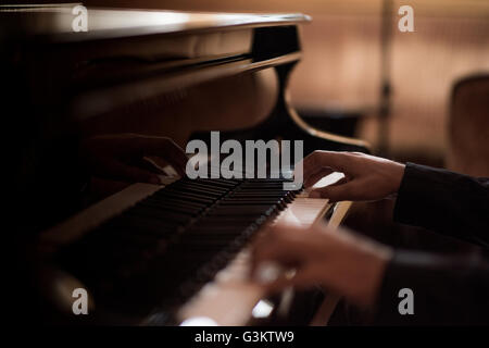 Le mani del giovane uomo giocando tasti di pianoforte nel bar di notte Foto Stock