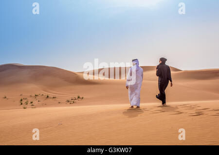 Giovane indossando il tradizionale del medio oriente a piedi vestiti nel deserto, Dubai, Emirati Arabi Uniti Foto Stock