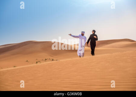 Giovane indossando il tradizionale medio orientale di puntamento vestiti dalle dune del deserto, Dubai, Emirati Arabi Uniti Foto Stock