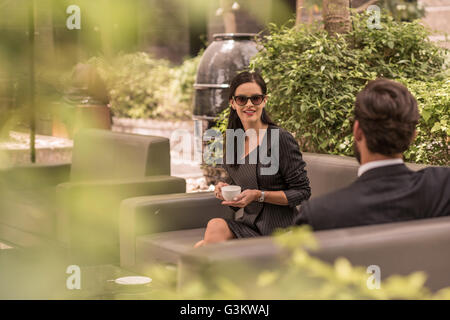 Imprenditore e la donna parlare su hotel divano da giardino, Dubai, Emirati Arabi Uniti Foto Stock