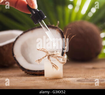 Noci di cocco e olio di noce di cocco sul tavolo di legno, su sfondo natura Foto Stock