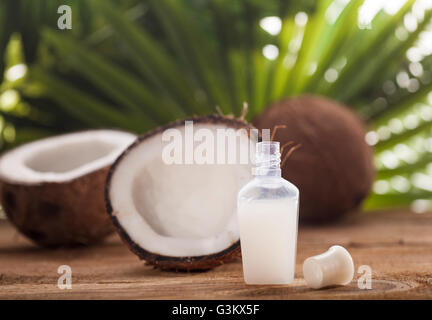 Noci di cocco e olio di noce di cocco sul tavolo di legno, su sfondo natura Foto Stock