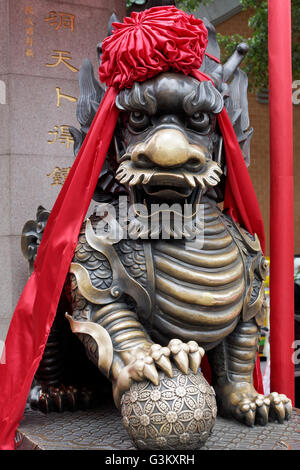 Custode di Lion, decorato con nastro rosso, Sik sik Yuen o Wong Tai Sin Tempio Taoista, Kowloon, Hong Kong, Cina Foto Stock