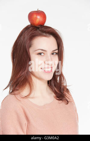 Sorridente giovane donna equilibratura di Apple sulla sua testa Foto Stock