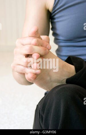 Femmina praticante yoga eseguendo un eka pada hasta mudra (mani e piedi) posizione in studio Foto Stock