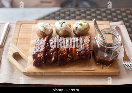 Consiglio di amministrazione di nervature di barbecue e potatoe su legno Foto Stock