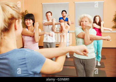 Senior donna facendo pilates con un gruppo di persone in un centro fitness Foto Stock