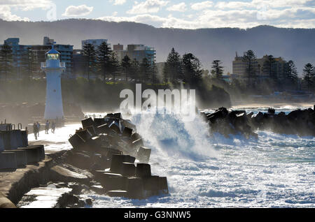 Grandi onde che si infrangono sulle persone sul porto di Wollongong breakwall vicino al faro, Nuovo Galles del Sud, Australia Foto Stock