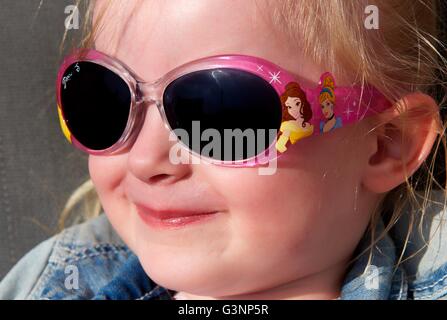 Un bambino di tre anni il toddler ragazza ridere indossando occhiali da sole Foto Stock