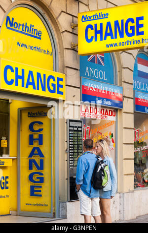 Coppia caucasica in piedi al di fuori di un scambio di denaro booth, Budapest, Ungheria Foto Stock