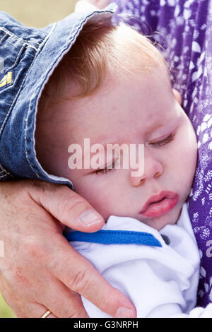 Bambino addormentato nella sua nonne bracci Foto Stock