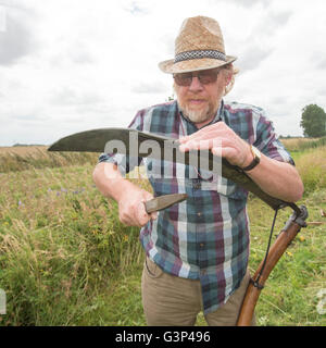 Un Inglese scything un campo nella campagna di Norfolk in Inghilterra. Foto Stock