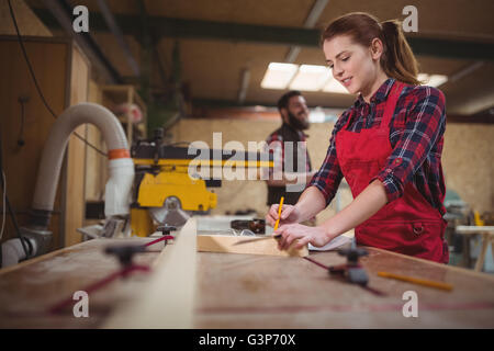 Falegname femmina la marcatura su tavola in legno con la matita Foto Stock