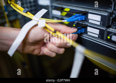 Close-Up del tecnico collegando il cavo patch in un rack server Foto Stock