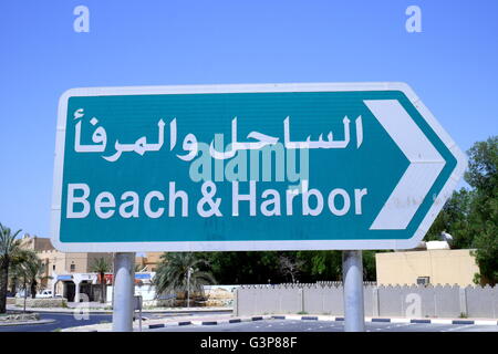 Cartello stradale che indica la spiaggia ed il porto in inglese e arabo nel villaggio di Al Jasra, Regno del Bahrein Foto Stock
