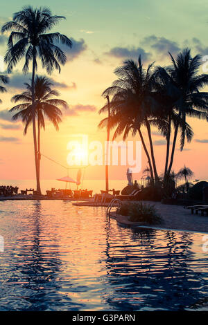 Bel tramonto con palme sagome su una spiaggia tropicale. Foto Stock
