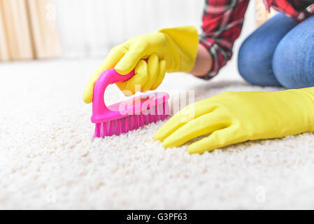Mani femminili nella spazzola guanti loro tappeti spazzola. Foto Stock