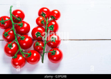 Bellissimo sfondo organico sani un ramo di pomodori ciliegini sulle lavagne bianche con spazio libero per voi il testo Foto Stock