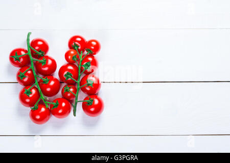 Bellissimo sfondo organico sani un ramo di pomodori ciliegini sulle lavagne bianche con spazio libero per voi il testo Foto Stock