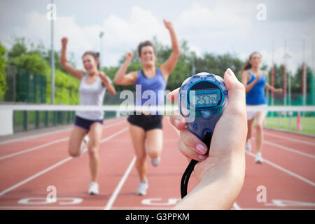 Immagine composita di una donna tenendo un cronometro per misurare le prestazioni Foto Stock
