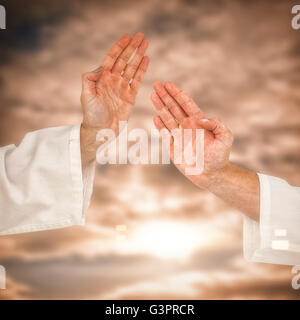 Combattente donna eseguendo il karate posizione contro il cielo nuvoloso Foto Stock