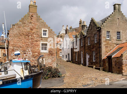 Barca da pesca e vecchie case su strada di ciottoli dal porto nel villaggio sul Firth of Forth costa. Crail East Neuk Fife Scozia UK Foto Stock