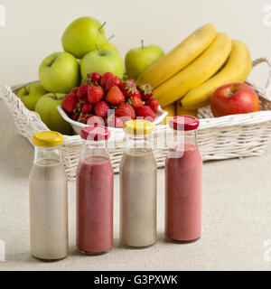 Cesto di frutta e fragola e banana smoothie in una bottiglia di vetro. Messa a fuoco selettiva. Foto Stock