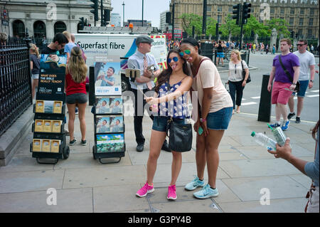 Due giovani turisti femmina tirando i volti mentre prendendo un selfie davanti alla Casa del Parlamento. Foto Stock