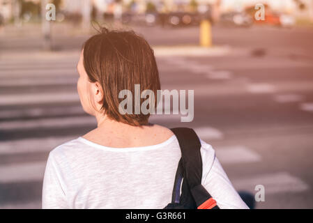 Casual giovane donna adulta camminando sulle strade della città, da dietro, il fuoco selettivo Foto Stock