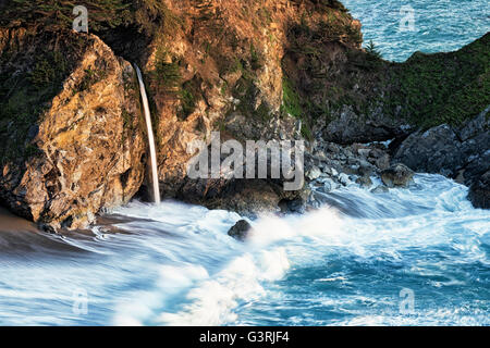 Luce della Sera bagna Julia Pfeiffer Burns State Park come McWay cade riversa nell'Oceano Pacifico lungo la California's Big Sur. Foto Stock