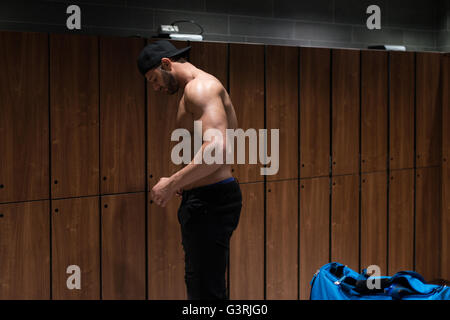 Montare giovane adulto uomo cambiare guarnizioni in spogliatoio della palestra Foto Stock