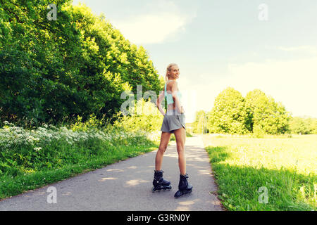 Felice giovane donna in rollerskates maneggio all'aperto Foto Stock