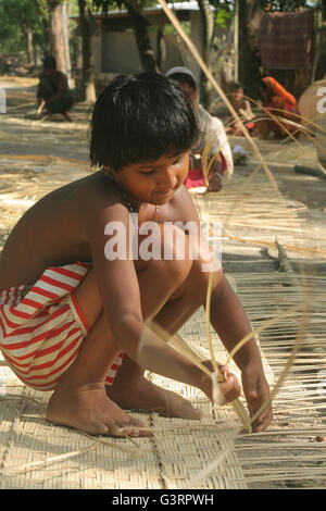 Un bambino facendo un cesto di bambù .Mangla,Bangladesh. Foto Stock